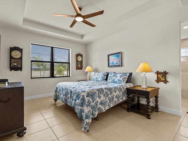 tiled bedroom with ceiling fan and a tray ceiling