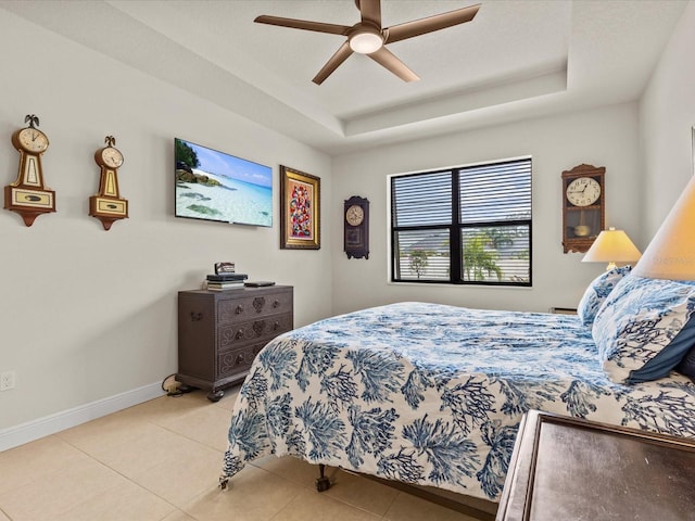 bedroom with light tile patterned flooring, ceiling fan, and a raised ceiling