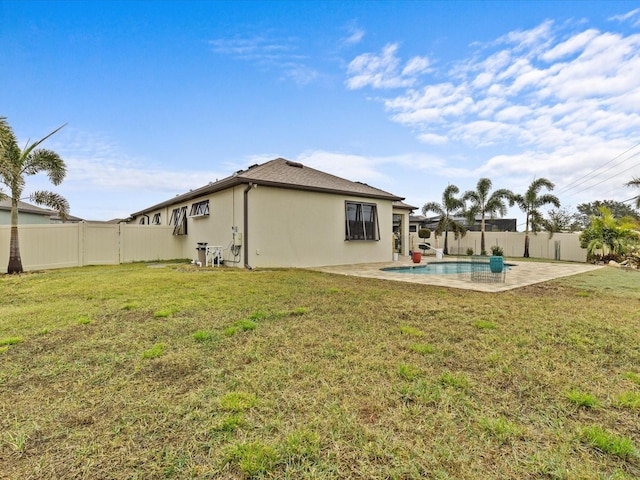 back of property with a fenced in pool, a lawn, and a patio area