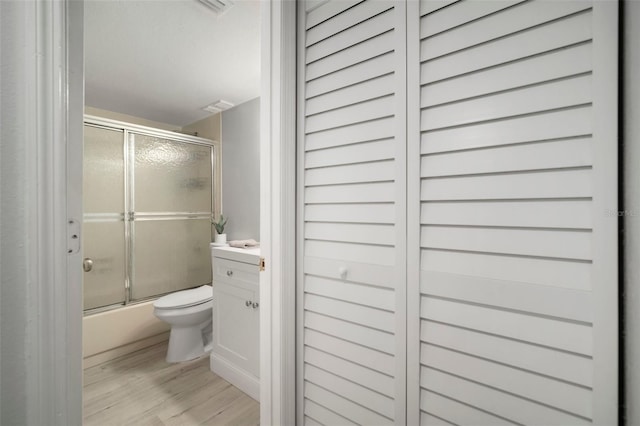 full bathroom featuring vanity, toilet, enclosed tub / shower combo, and wood-type flooring