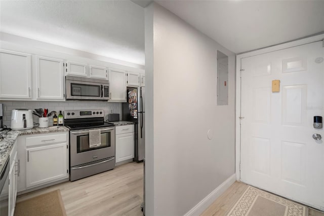 kitchen featuring decorative backsplash, white cabinets, and stainless steel appliances