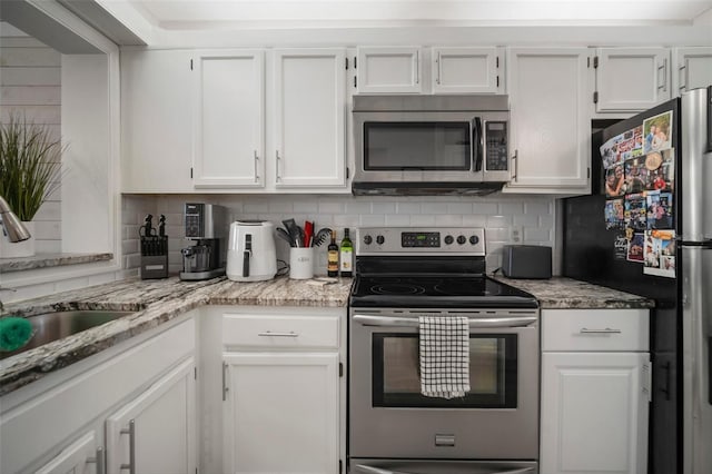 kitchen with decorative backsplash, white cabinets, sink, stainless steel appliances, and light stone counters