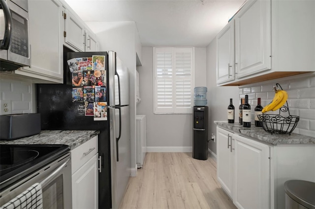 kitchen featuring backsplash, white cabinets, light stone countertops, light hardwood / wood-style floors, and stainless steel appliances