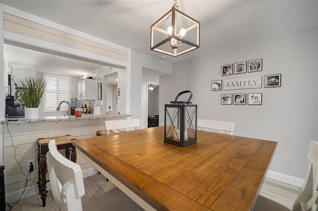 dining room with sink, a notable chandelier, and light hardwood / wood-style floors