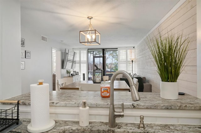 kitchen with decorative light fixtures, a notable chandelier, and light stone counters