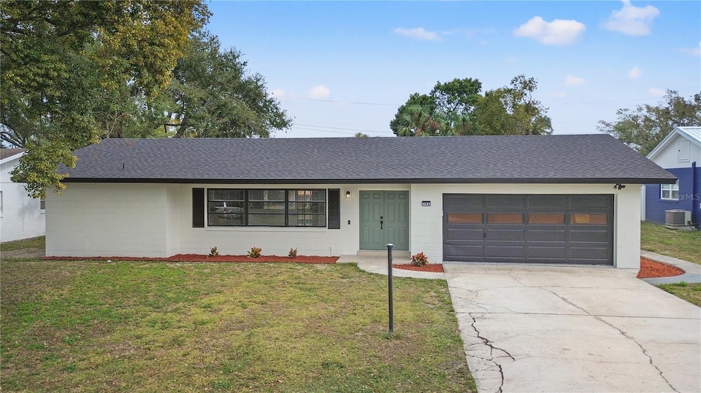 single story home with a garage, cooling unit, and a front lawn