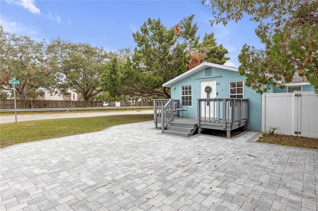 back of property featuring a wooden deck, a lawn, and a patio