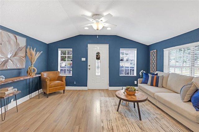 living room with light hardwood / wood-style floors, a wealth of natural light, ceiling fan, and vaulted ceiling