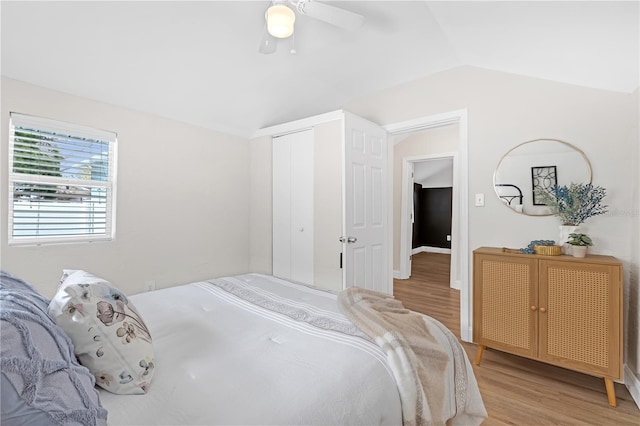 bedroom with vaulted ceiling, ceiling fan, a closet, and light hardwood / wood-style floors