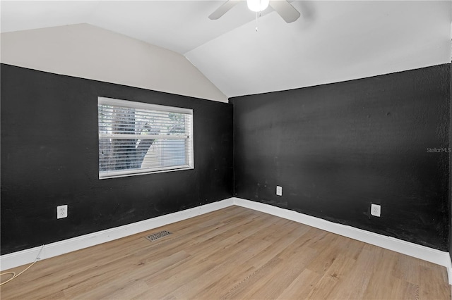 empty room with ceiling fan, wood-type flooring, and vaulted ceiling