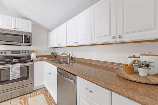 kitchen with sink, white cabinets, light tile patterned floors, and stainless steel appliances