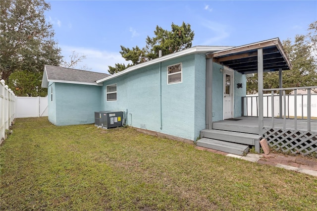 rear view of property with a wooden deck, central AC, and a yard