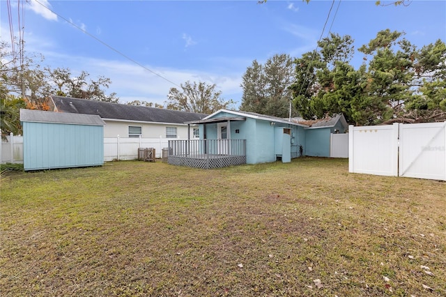 back of house with a storage shed, a deck, and a yard