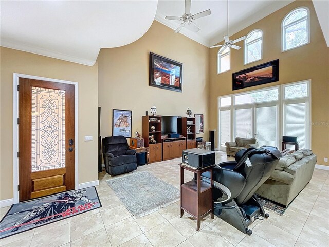 tiled living room with ceiling fan, a high ceiling, and crown molding