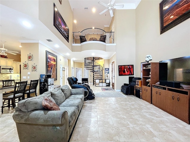 tiled living room with ceiling fan, crown molding, and a towering ceiling