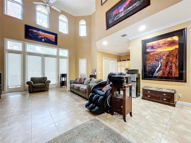 tiled living room featuring ceiling fan, a high ceiling, and crown molding