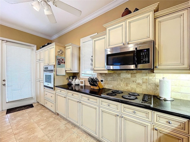 kitchen featuring light tile patterned flooring, appliances with stainless steel finishes, crown molding, and cream cabinets