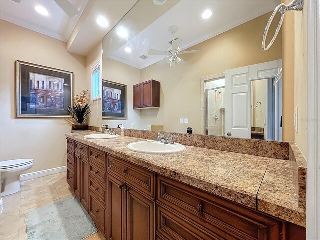 bathroom featuring ceiling fan, vanity, toilet, ornamental molding, and a shower with door