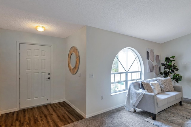 entryway with dark wood-type flooring and a textured ceiling