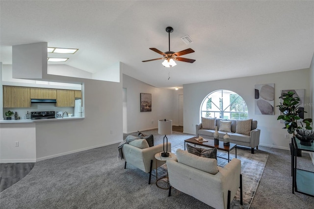 carpeted living room with ceiling fan and vaulted ceiling