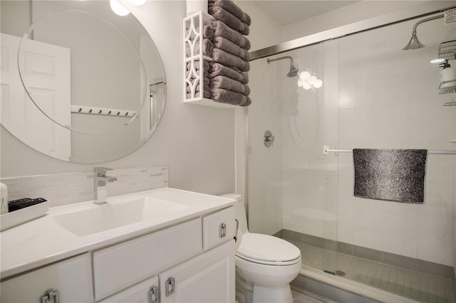 bathroom with toilet, tasteful backsplash, walk in shower, and vanity