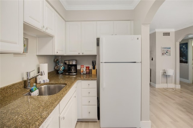 kitchen featuring sink, white cabinets, light wood-type flooring, dark stone counters, and white refrigerator