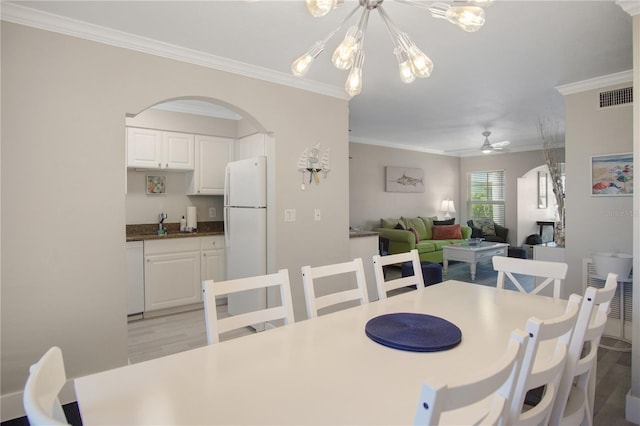 dining room with ceiling fan with notable chandelier, crown molding, and light wood-type flooring