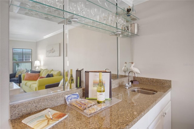 kitchen with sink, white cabinetry, crown molding, and stone countertops