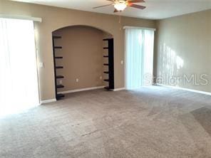 empty room featuring carpet, ceiling fan, and a wealth of natural light