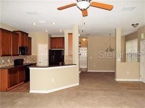 kitchen with ceiling fan, a kitchen island, decorative backsplash, and black refrigerator