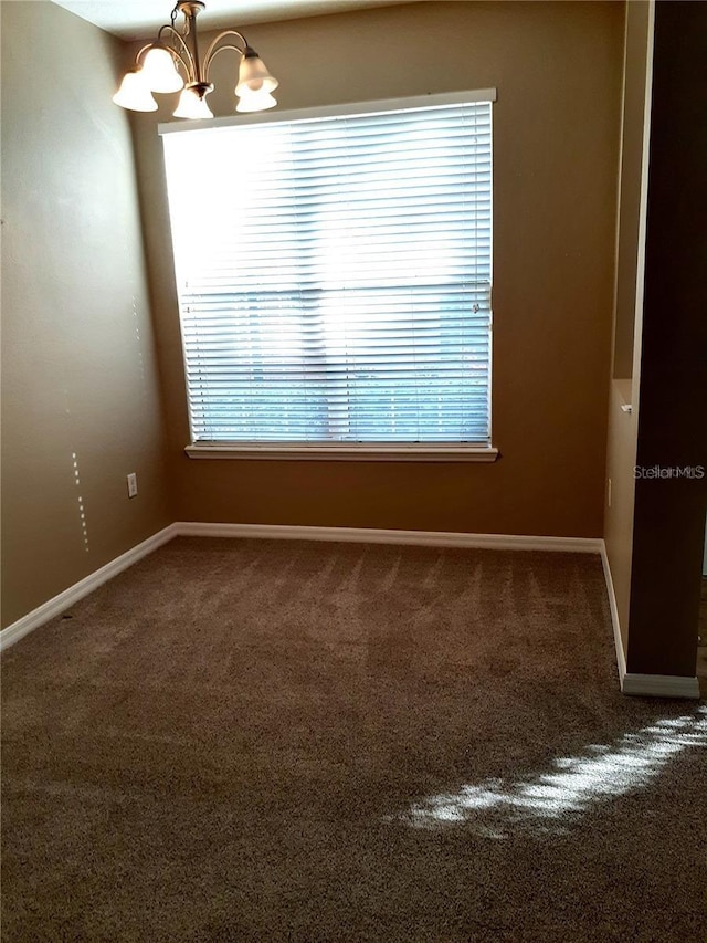 carpeted spare room with a chandelier