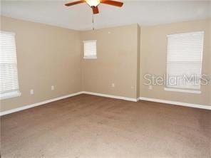 carpeted spare room with ceiling fan and a healthy amount of sunlight