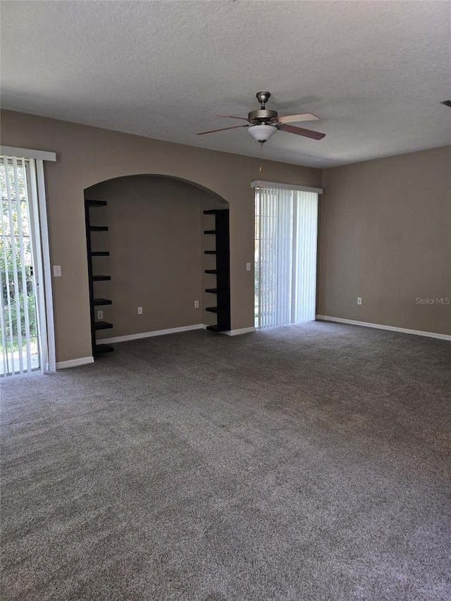 6769 Breezy Palm Dr, Riverview, FL 33578 - empty room with arched walkways, a ceiling fan, plenty of natural light, a textured ceiling, and baseboards