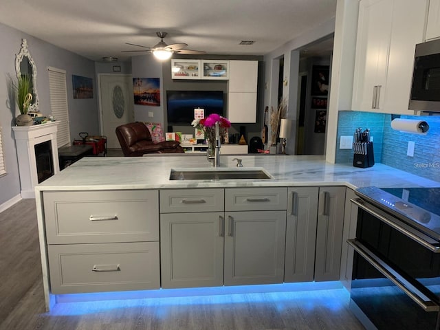 kitchen featuring appliances with stainless steel finishes, tasteful backsplash, sink, kitchen peninsula, and light wood-type flooring