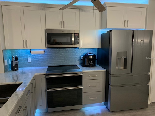 kitchen featuring ceiling fan, appliances with stainless steel finishes, white cabinetry, tasteful backsplash, and light wood-type flooring