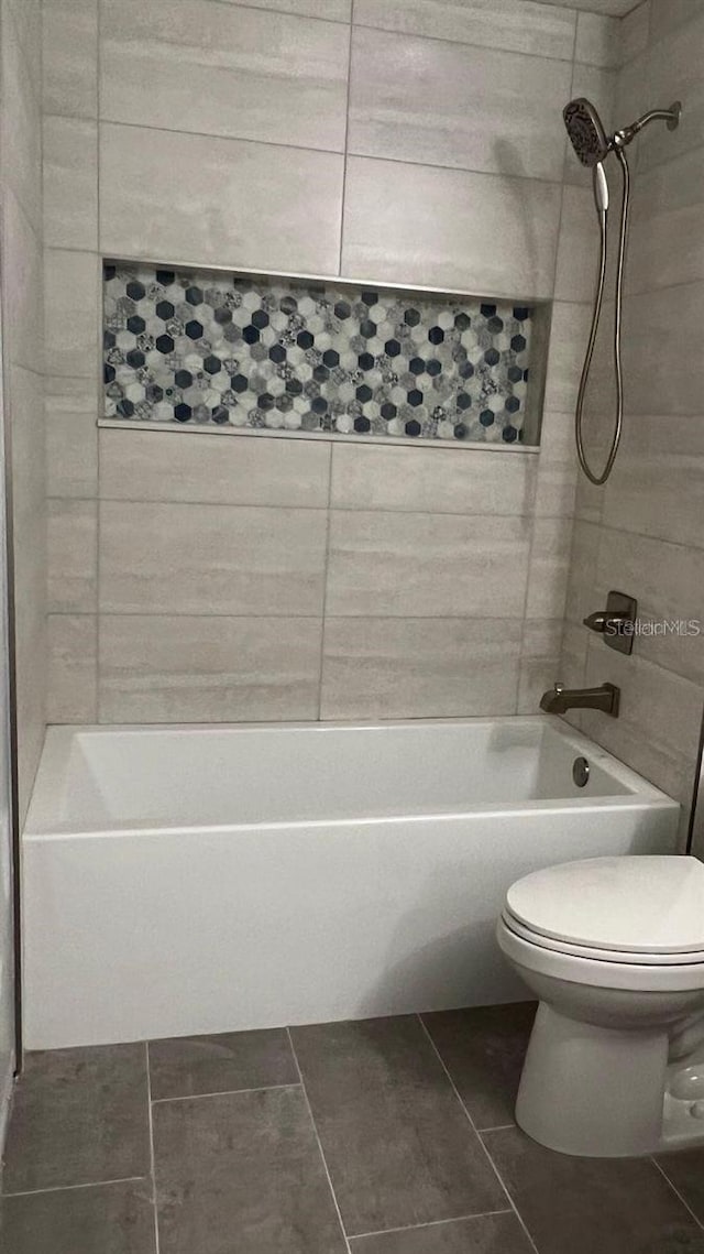 bathroom featuring tile patterned flooring, tiled shower / bath, and toilet