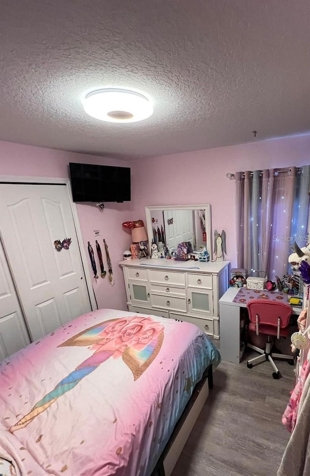 bedroom with light hardwood / wood-style flooring, a textured ceiling, and a closet