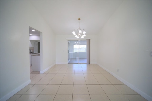 spare room with lofted ceiling, light tile patterned flooring, and a chandelier