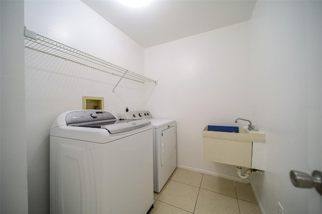 washroom featuring washing machine and dryer, light tile patterned floors, and sink