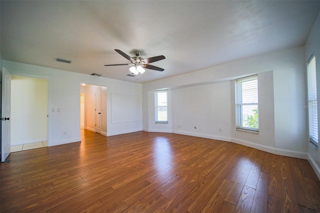 unfurnished room featuring ceiling fan, dark wood-type flooring, and plenty of natural light