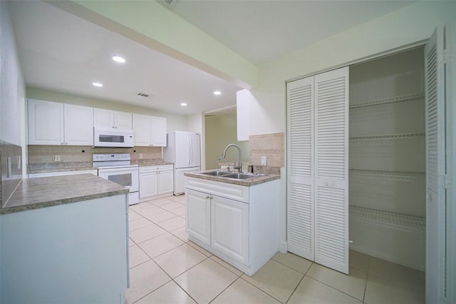 kitchen featuring tasteful backsplash, sink, light tile patterned floors, white appliances, and white cabinets