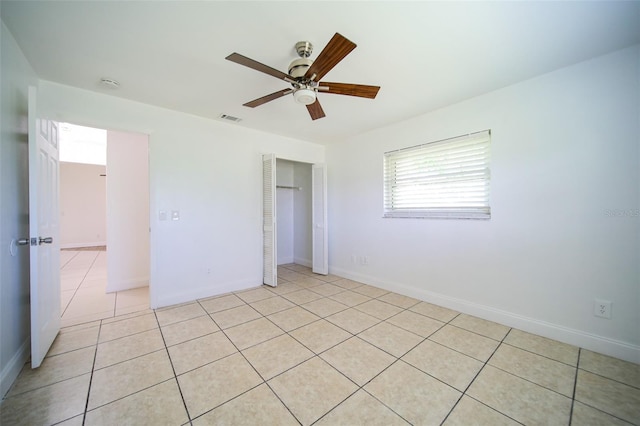 unfurnished bedroom with ceiling fan, light tile patterned flooring, and a closet