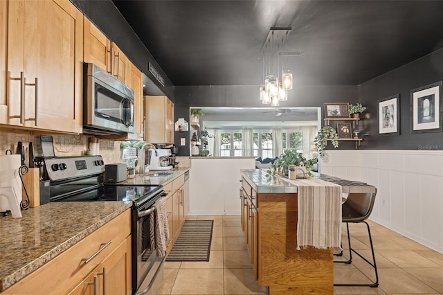 kitchen featuring light tile patterned floors, appliances with stainless steel finishes, sink, a breakfast bar, and a center island