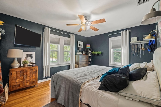 bedroom featuring ceiling fan, multiple windows, and light hardwood / wood-style flooring