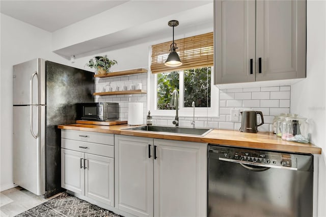 kitchen featuring tasteful backsplash, sink, wood counters, and black dishwasher