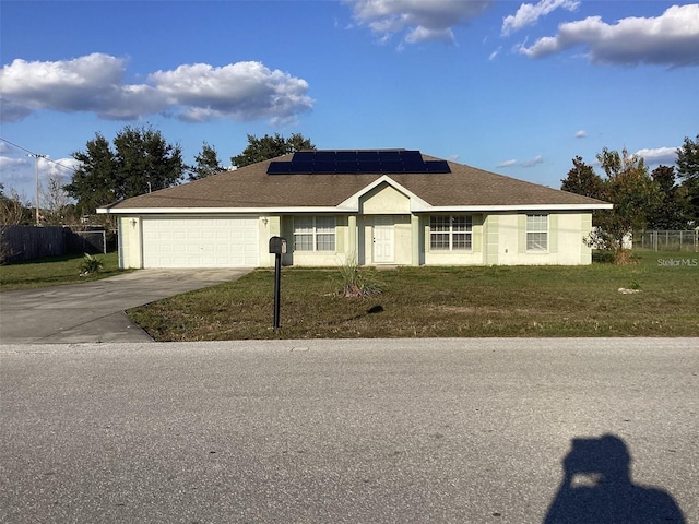 ranch-style home with a garage, a front yard, and solar panels