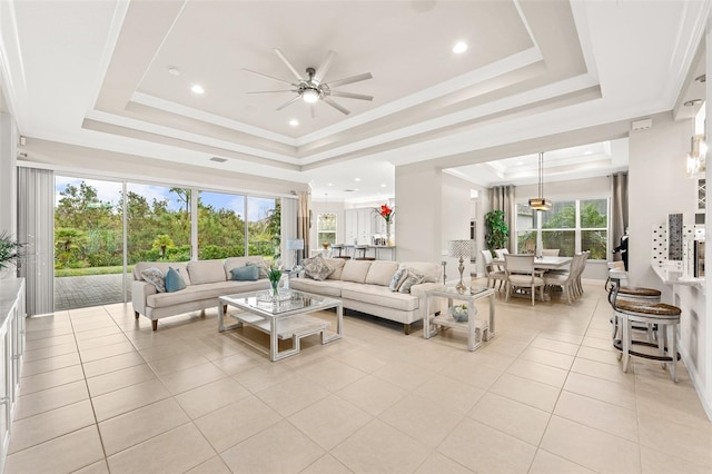 living area with light tile patterned floors, ceiling fan, recessed lighting, a raised ceiling, and crown molding