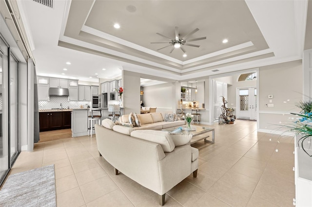 living area featuring a tray ceiling, crown molding, recessed lighting, and light tile patterned floors