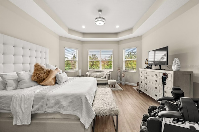 bedroom with baseboards, a tray ceiling, wood finished floors, and recessed lighting