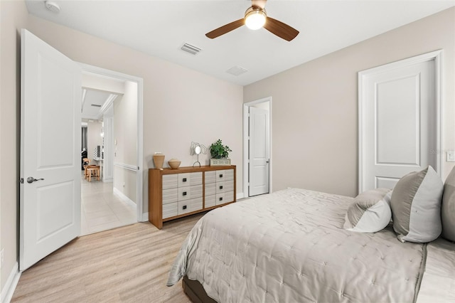 bedroom featuring light wood-style floors, visible vents, baseboards, and a ceiling fan